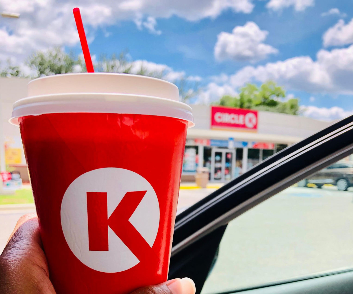 Hand holding Circle K drink outside of car window