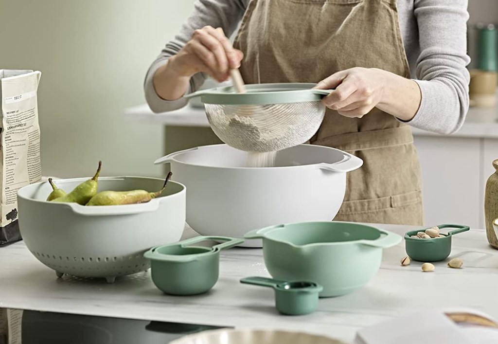 Person sifting flour into a mixing bowl