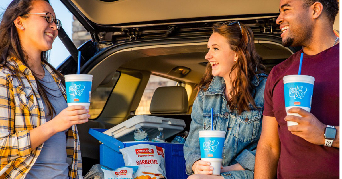 People standing in front of an open suv trunk, holding drinks from Circle K