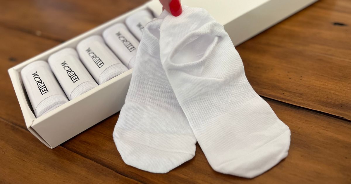 a womans hand holding up a pair of white Wernies socks next to a box of wernies socks