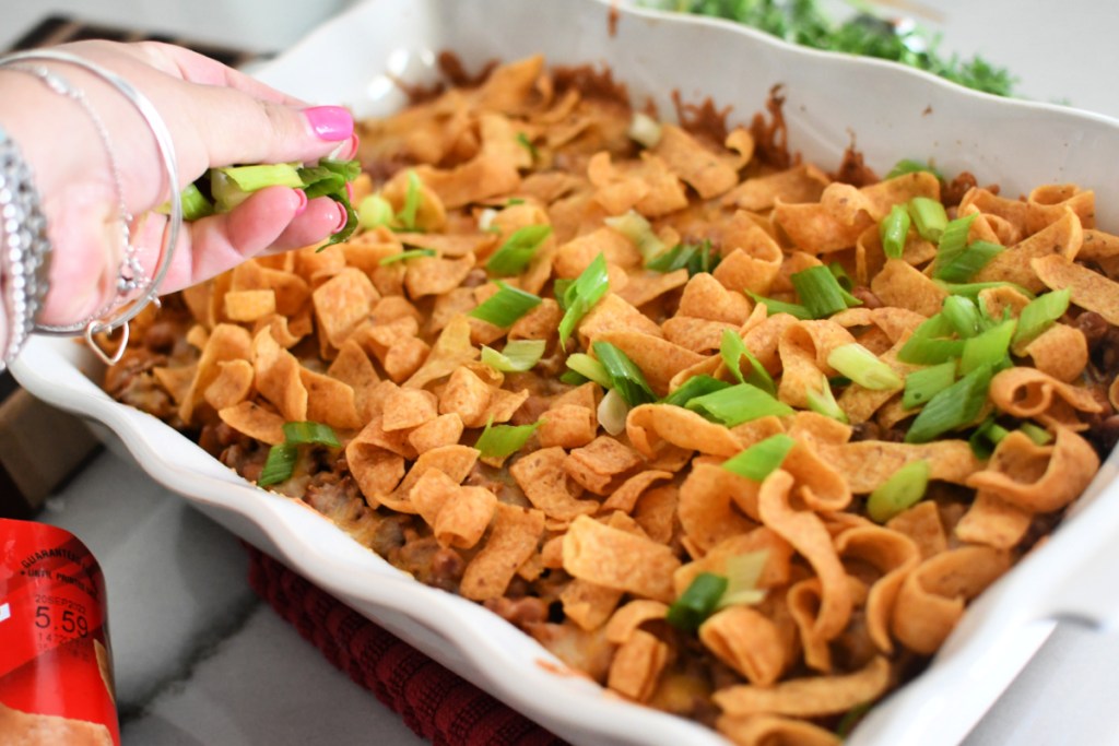 addng fritos and sliced onion to frito pie