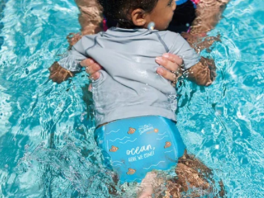 little kid swimming with diapers in a pool