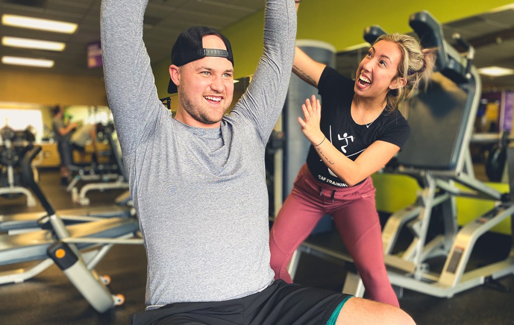 man lifting weights smiling in gym