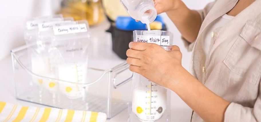 a woman pouring breat milk into a medela storage bag