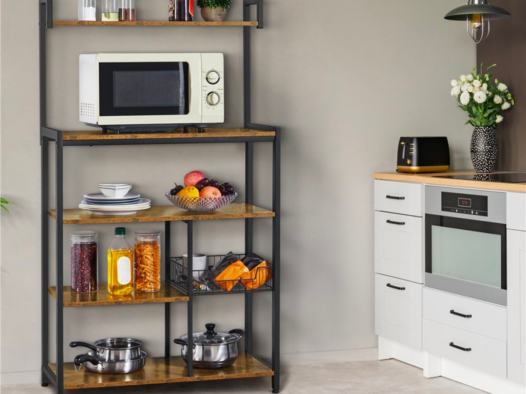 metal and wood bakers rack with microwave , fruit bowls and other items on shelf