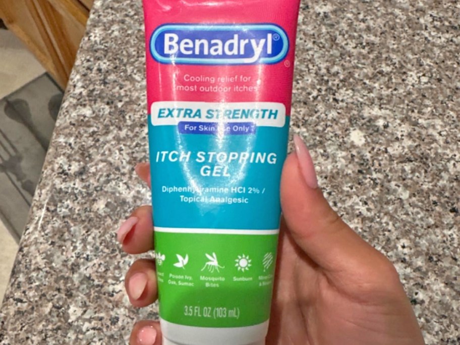 hand holding a pink, blue, and green tube of Benadryl Extra Strength Anti-Itch Gel