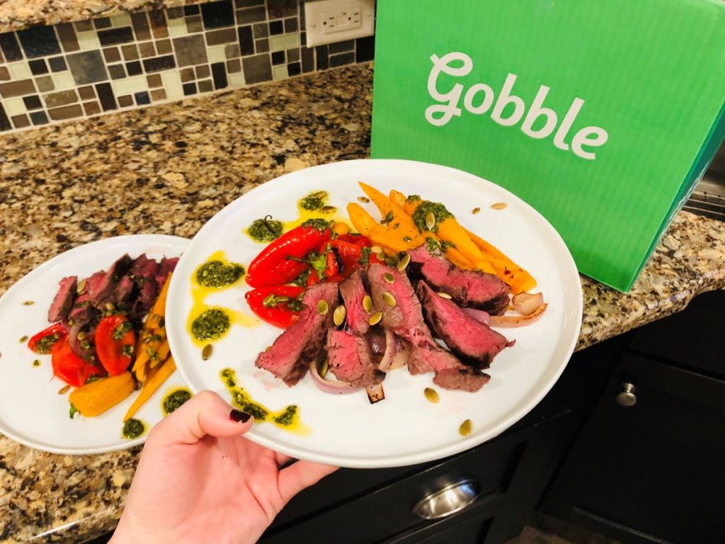 hand holding a plate of food by a Gobble box