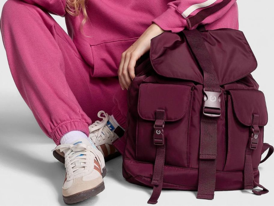 A woman sitting next to a rose-colored backpack