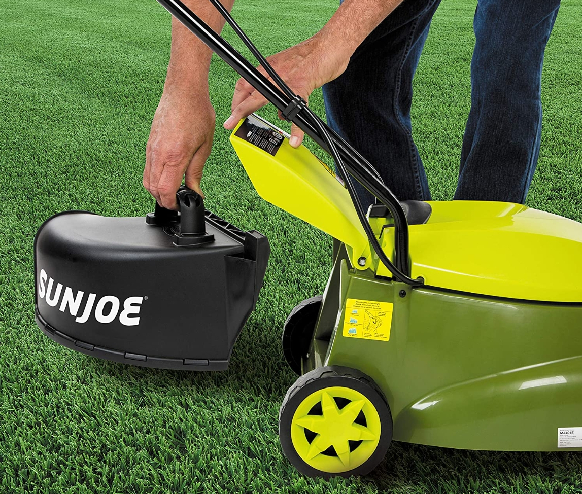 person putting a cuttings bag on a Sun joe electric lawn mower