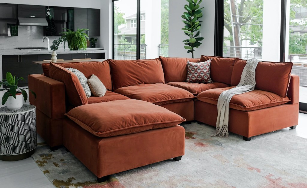 red velvet couch in living room in front of black modern kitchen