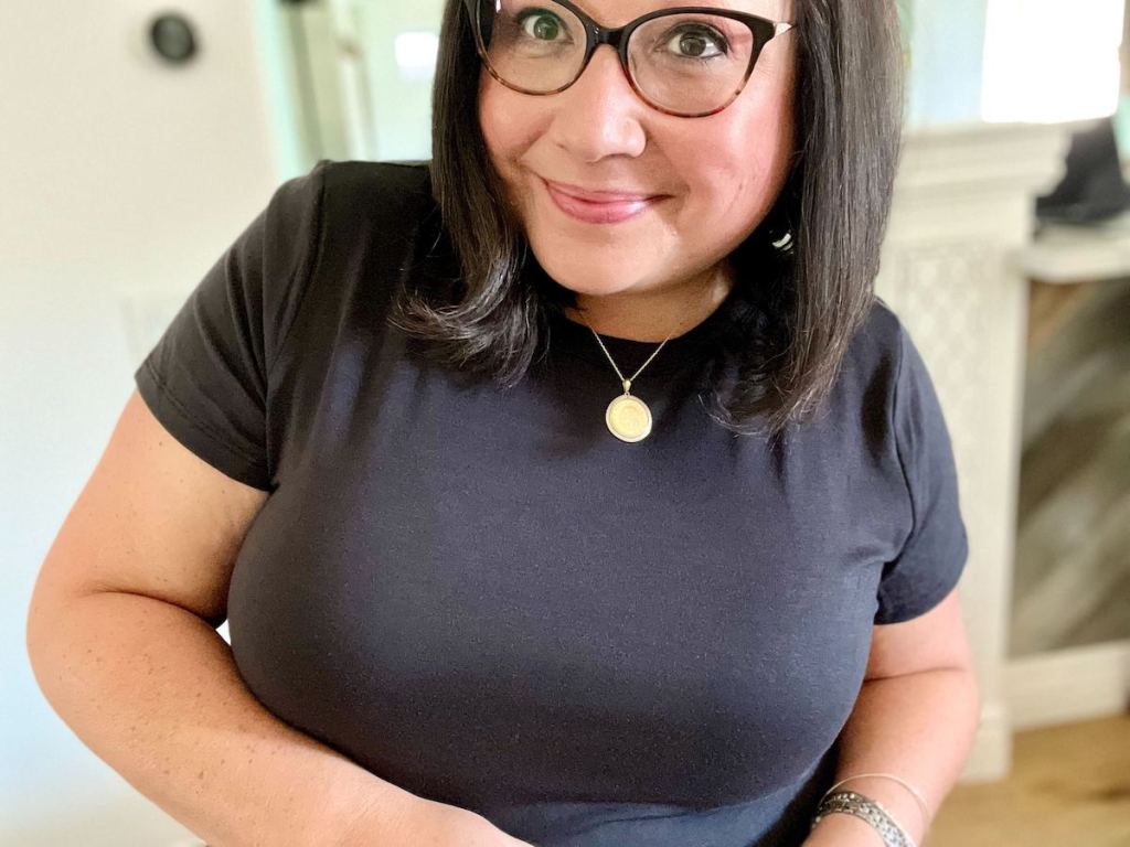 woman smiling wearing gold coin necklace and black shirt