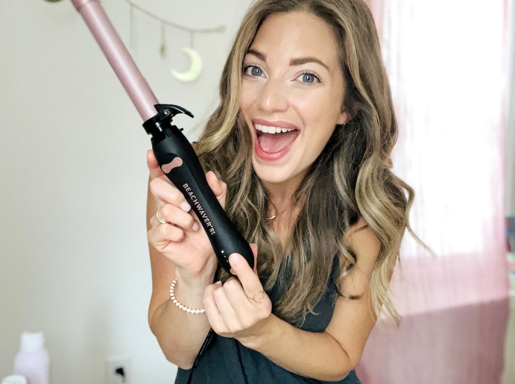 woman holding beachwaver curling iron smiling