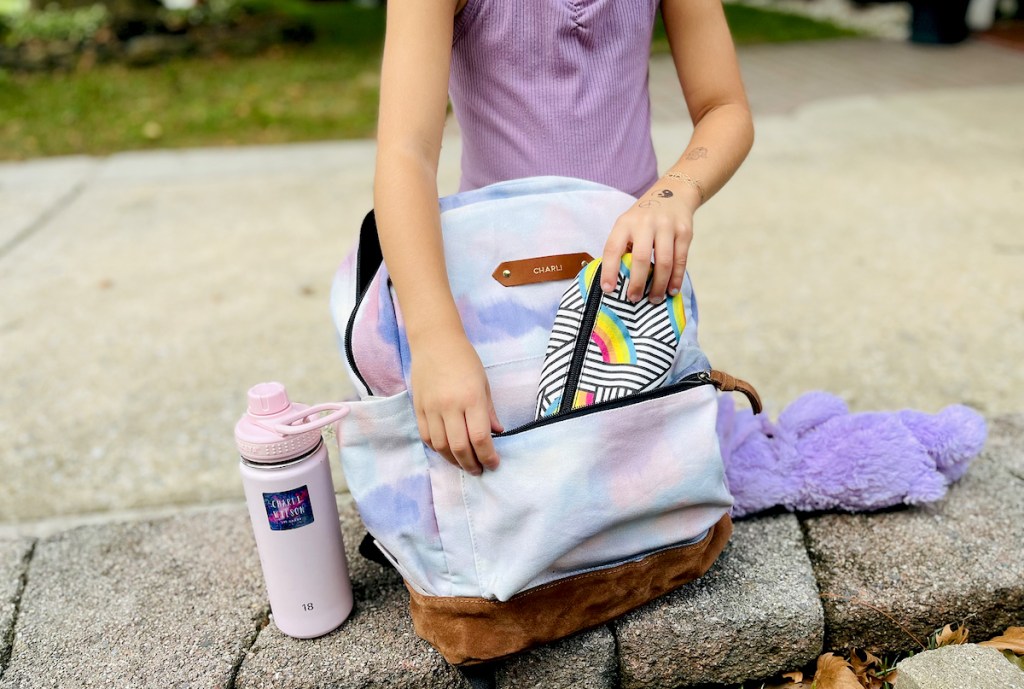 girl putting pencil case in tie dye bookbag