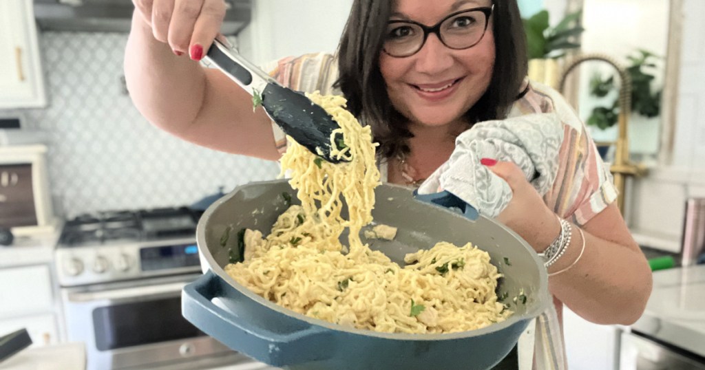 woman holding skillet with chicken alfredo ramen