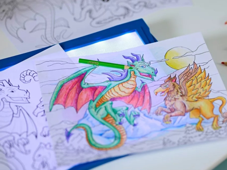 a drawing of a dragon and other drawings on a blue and white light up tracing pad