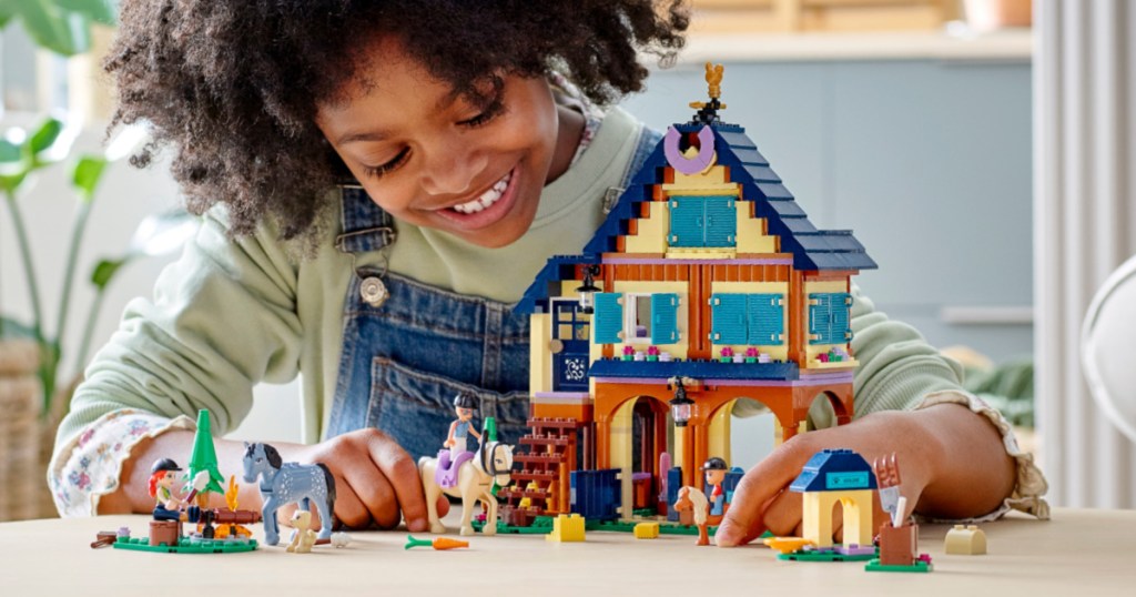 girl playing with ranch and stable playset