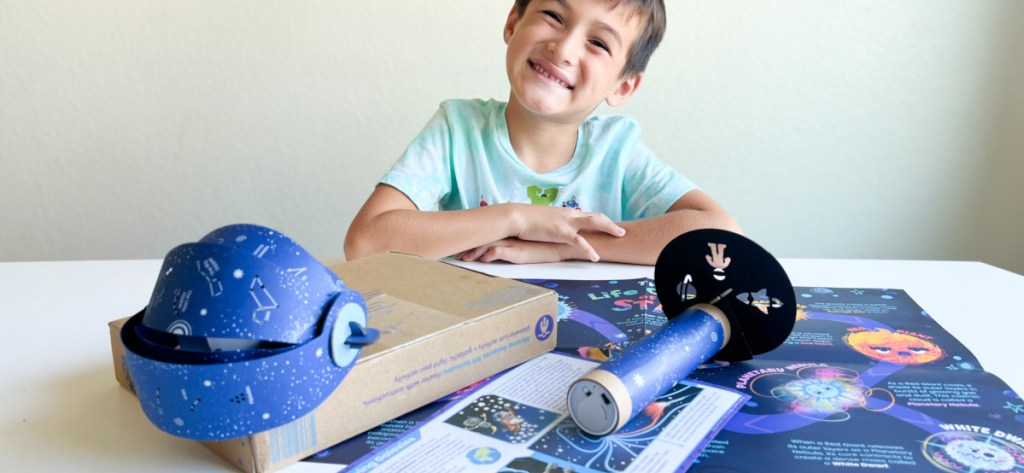 boy playing with Little Passports box filled with cool toys