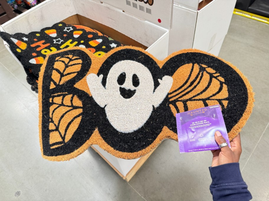 Hand holding a Halloween Doormat from Lowe's in the shape of a ghost