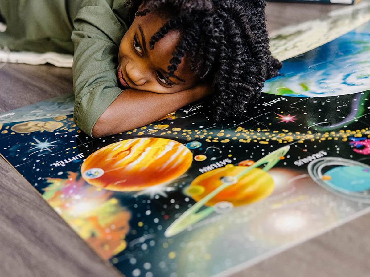 child laying on floor, with onlinepleted solar system floor puzzle