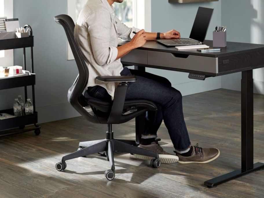 A man sitting in a black office chair at his desk