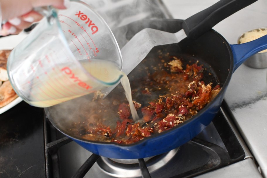 adding broth to chicken skillet meal