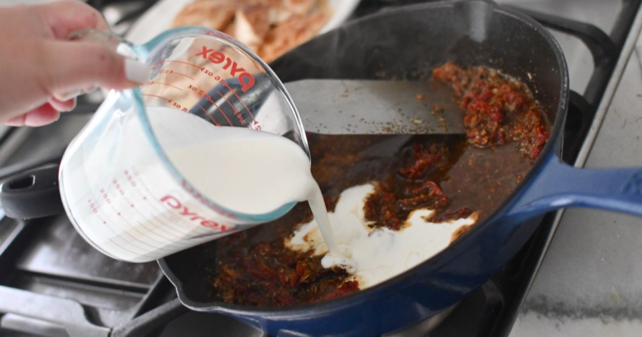 adding cream to skillet sun-dried tomato chicken