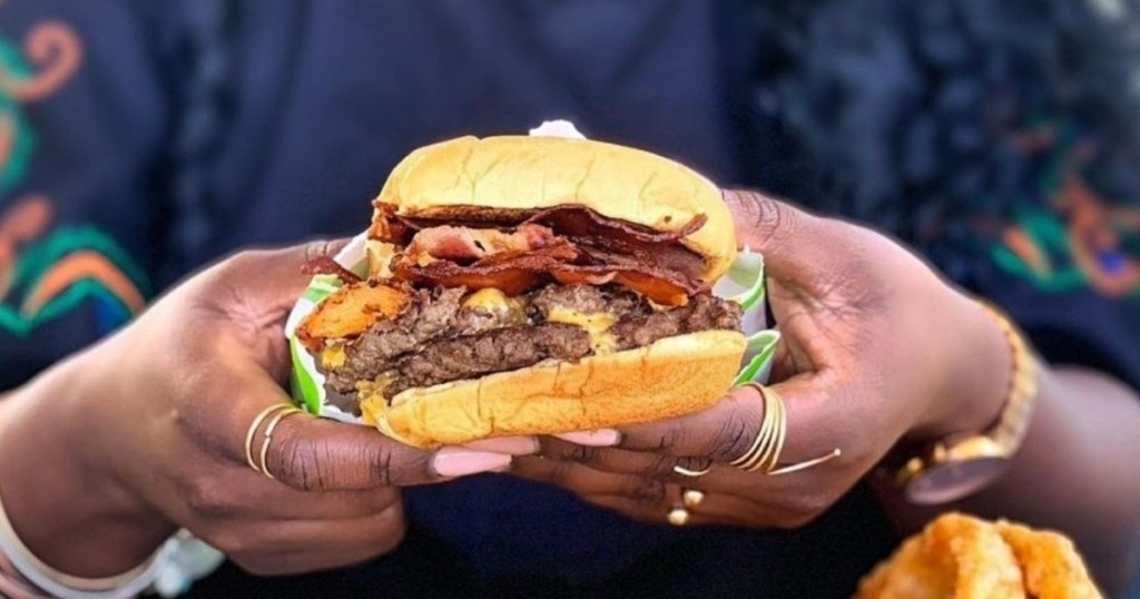 holding a cheeseburger with 2 hands