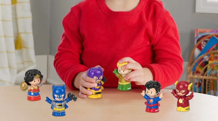 a little boy playing with a set of super hero friends little people toys