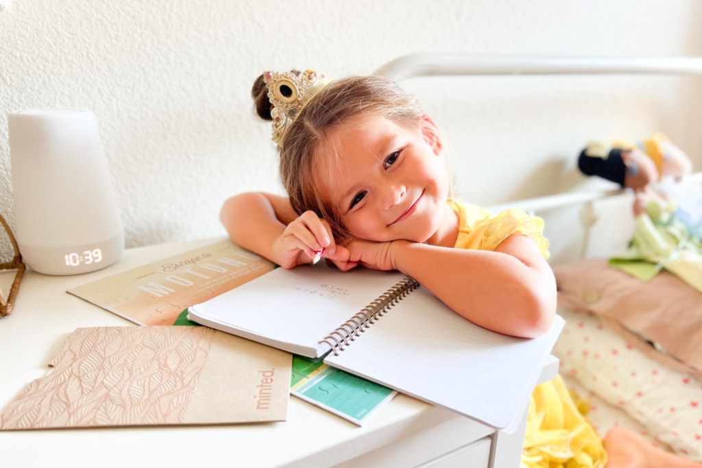 girl writing in Disney Minted notebook