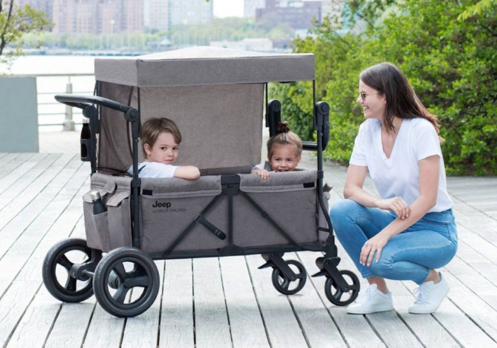 woman kneeling next to stroller wagon full of kids