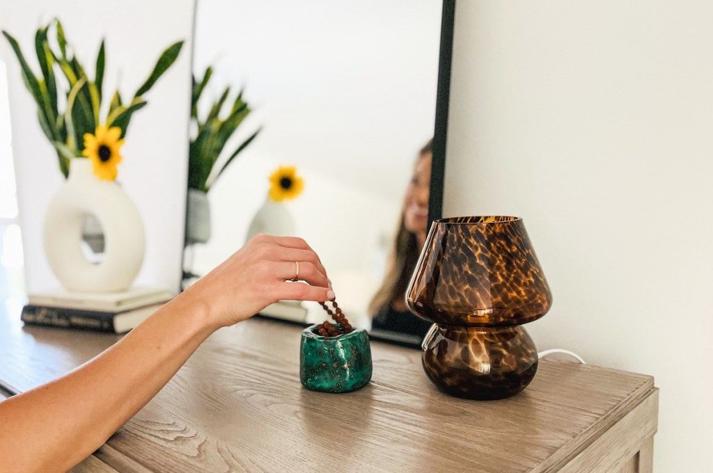 hand taking beaded necklace out of dish next to walmart fall bedroom decor