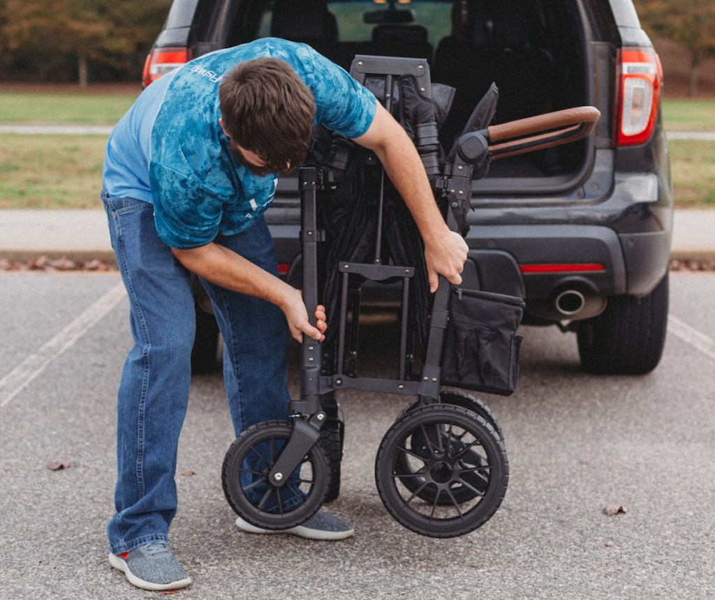 man folding wagon in front of open car trunk