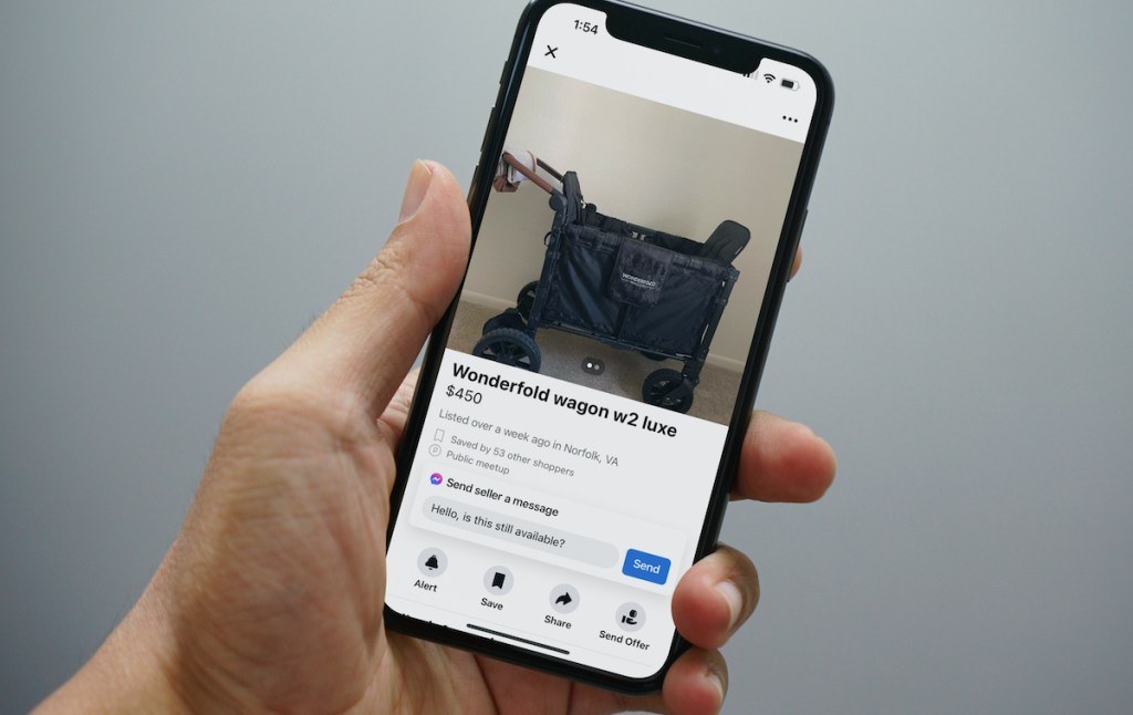 man holding phone with screenshot of wonderfold wagon listing on facebook marketplace