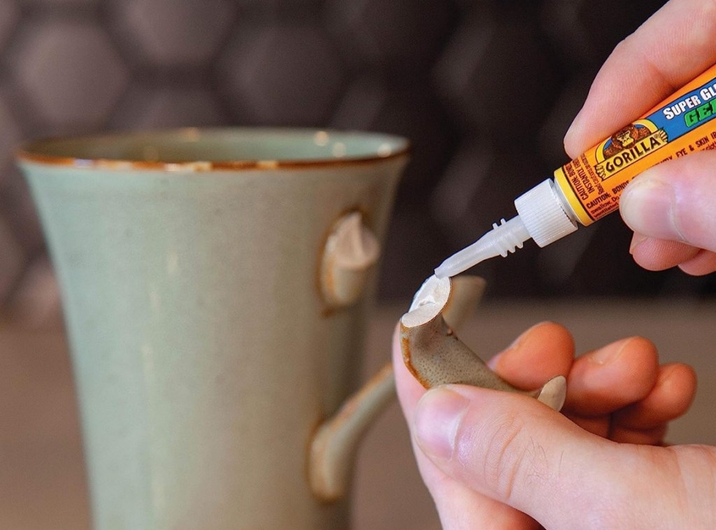 Hand applying super glue to a mug