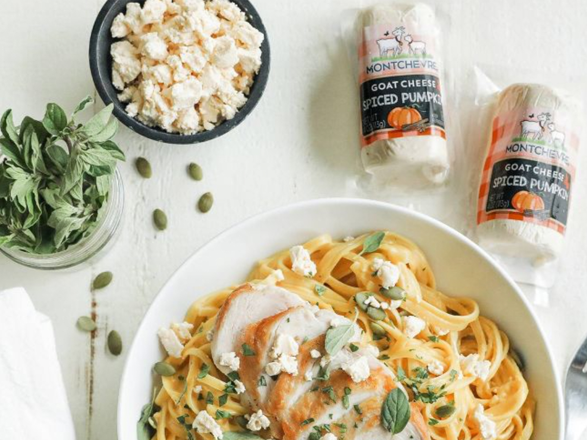 two packages of montchevre goat cheese near a dish of pasta and smaller dishes of herbs and crumbled cheese