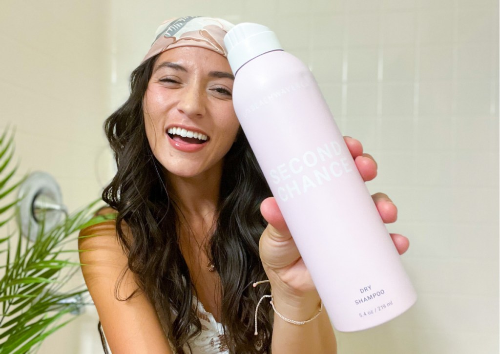 Woman holding pink bottle of beachwaver dry shampoo 