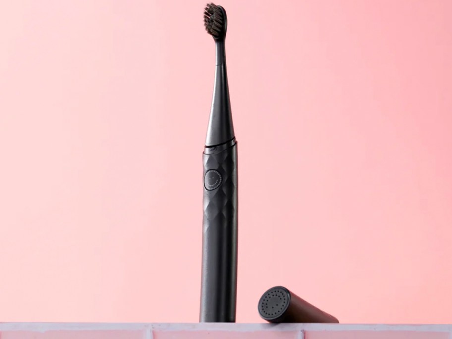 black toothbrush sitting on table with pink background 