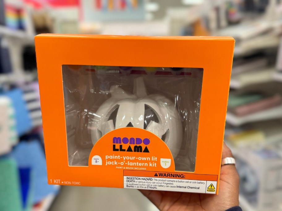 hand holding a box with a paint your own ceramic Jackolantern