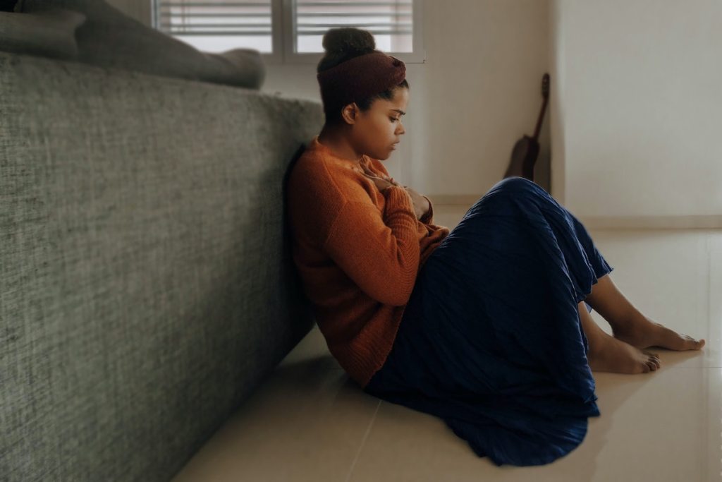 girl sitting on floor leaning on back of couch