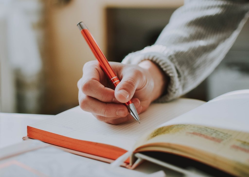 person hand writing in journal