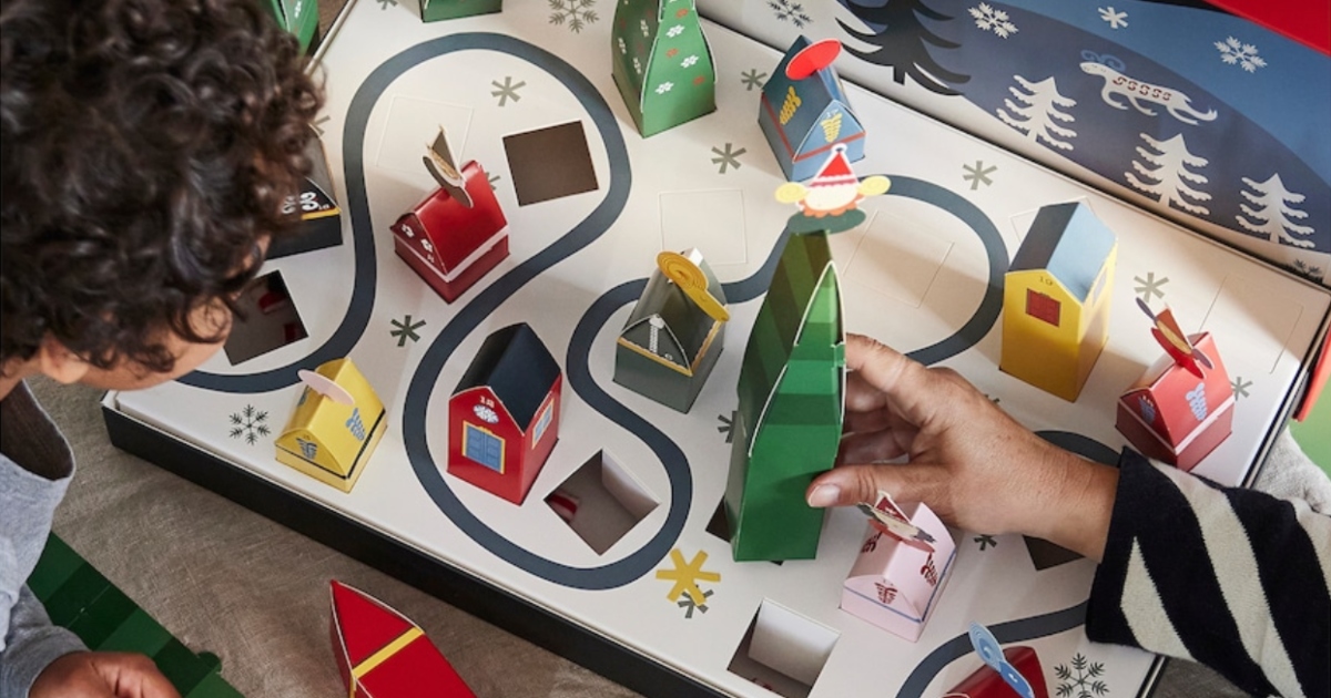 hands assembling a paper IKEA Advent calendar with a person watching