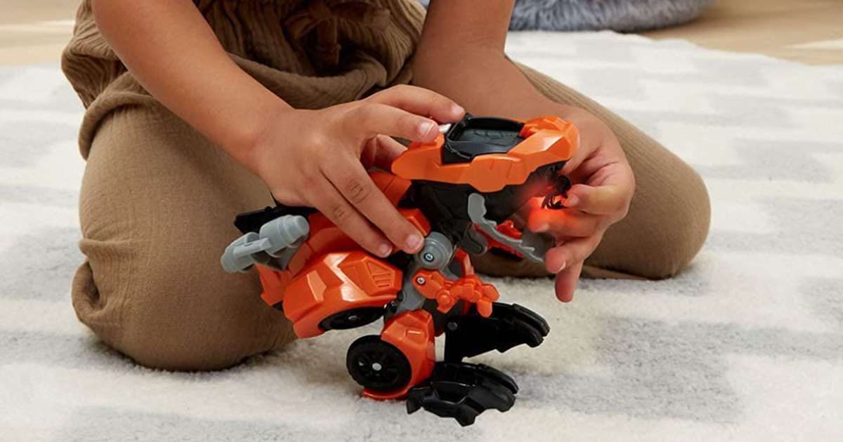 boy playing with a switch & go dinos t-rex toy on a rug