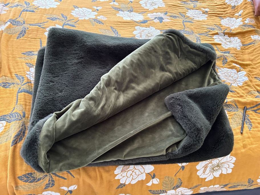 folded dark gray blanket on mustard yellow and white floral blanket