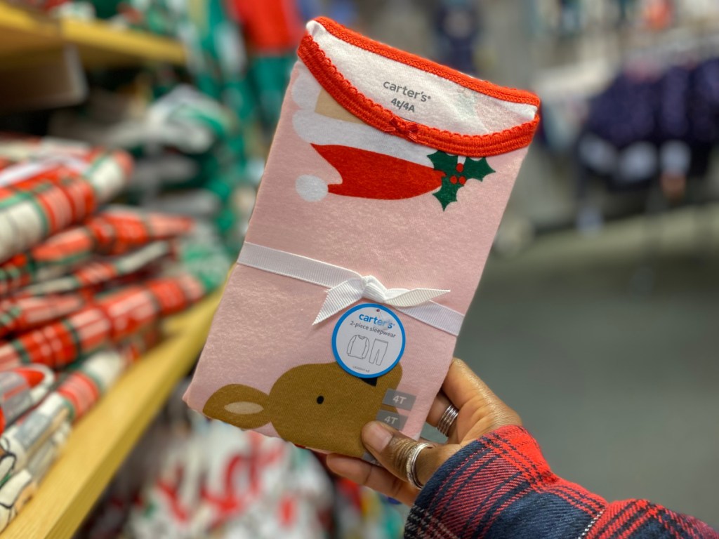 Person holding up Carters Pink Holiday Pajamas in store