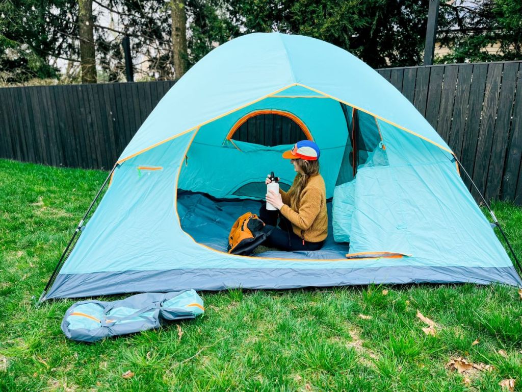 Woman sitting in a tent holding a water bottle