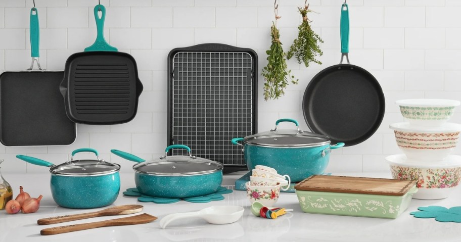 a set of teal and black cookware with mixing bowls, wood kitchen utensils, mixing bowls and baking dishes on a countertop