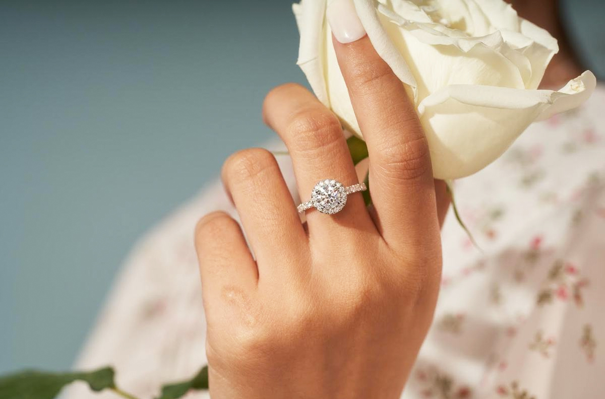 woman wearing ring and holding white rose