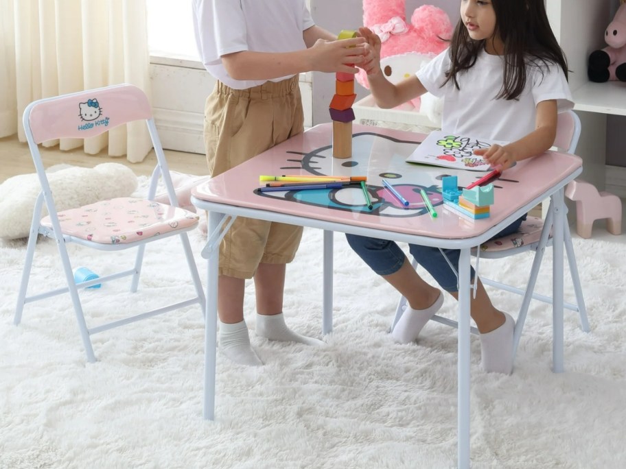 kids playing at a pink and white kid size table and chairs set with Hello Kitty on them