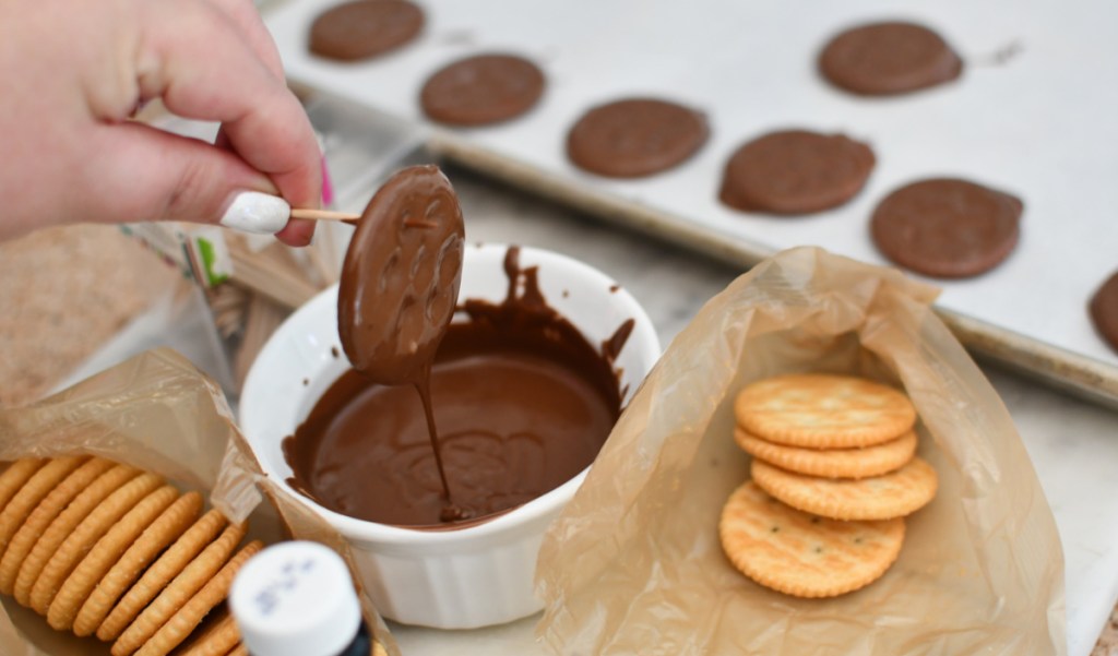 Dipping Ritz crackers in chocolate to create homemade thin mints