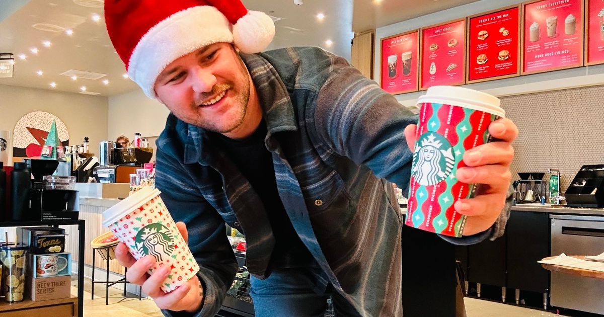 man in a Santa hat holding starbucks coffee cups